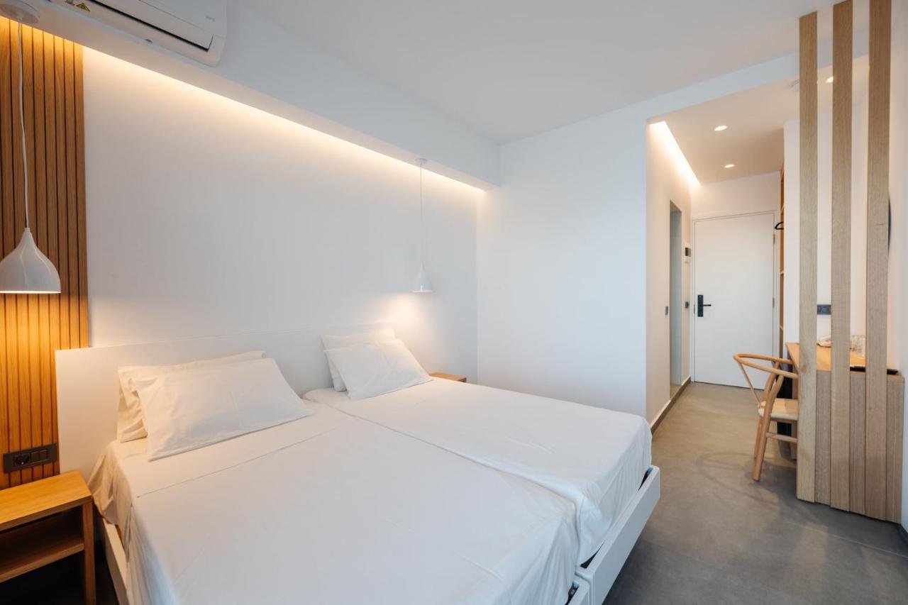 een slaapkamer met een groot wit bed en een tafel bij Pontikonisi Hotel & Suites-Adults Only in Perama