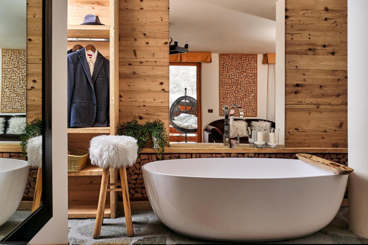 een badkuip in een badkamer met houten wanden bij Boutique Hotel e Chalets Salvadori in Mezzana