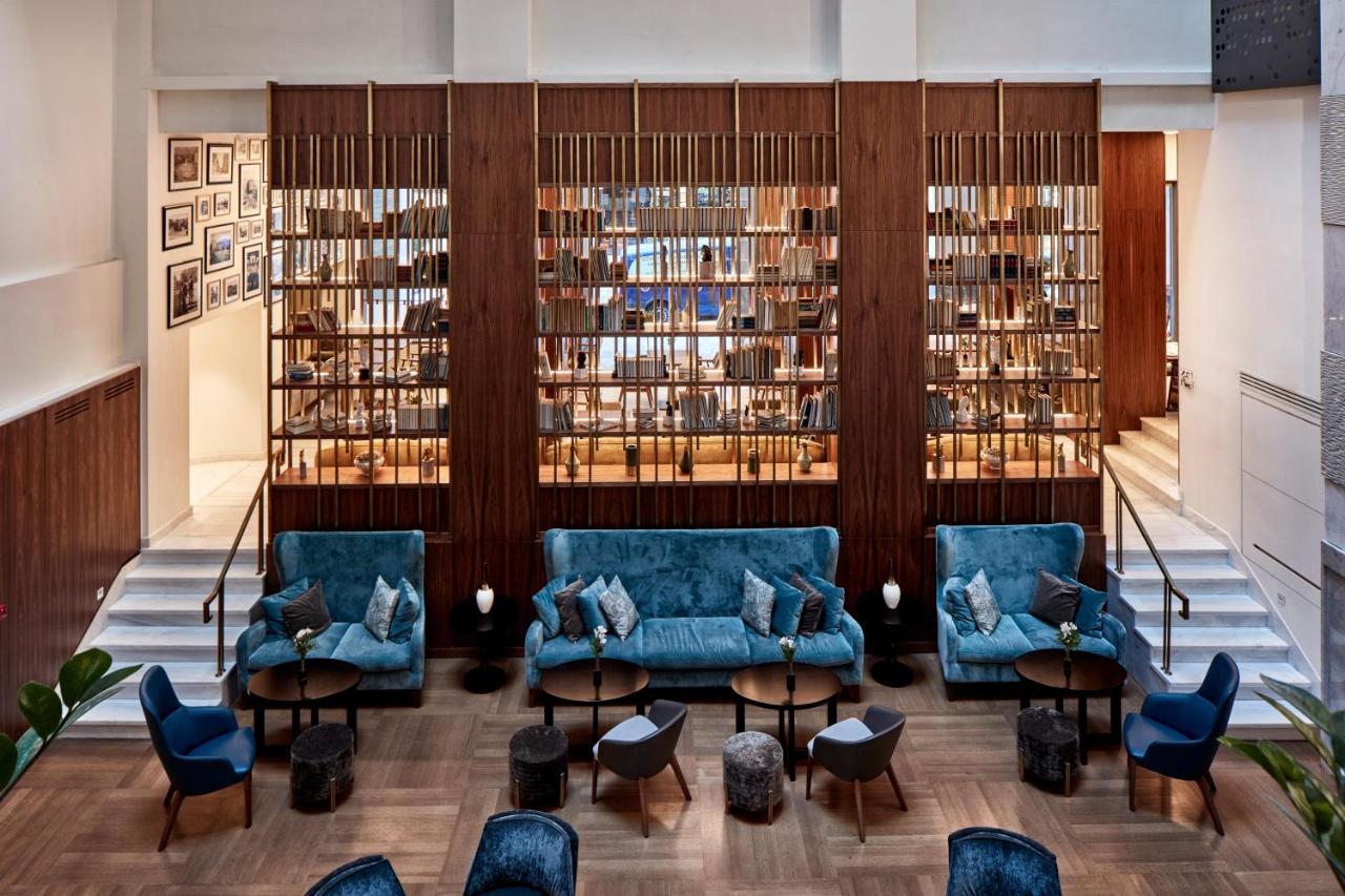 een bibliotheek met blauwe banken en tafels en boeken bij Electra Metropolis in Athene