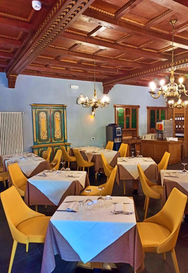 een eetkamer met tafels en gele stoelen bij GH Hotel Monzoni in Pozza di Fassa