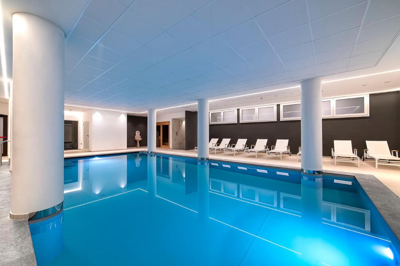 een zwembad met blauw water in een gebouw bij Hotel Shandranj in Tesero +43 foto's