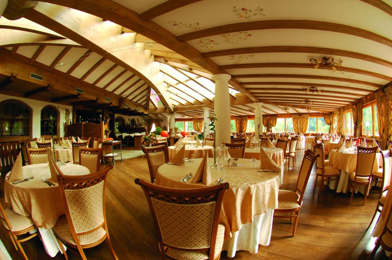 een restaurant met tafels en stoelen in een ruimte bij Hotel Shandranj in Tesero