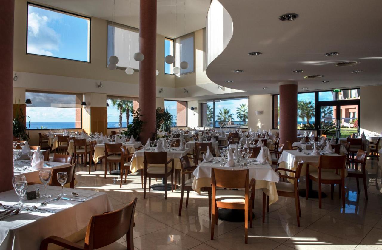 een restaurant met witte tafels en stoelen en ramen bij Monte Mar Palace Hotel in Ponta Delgada