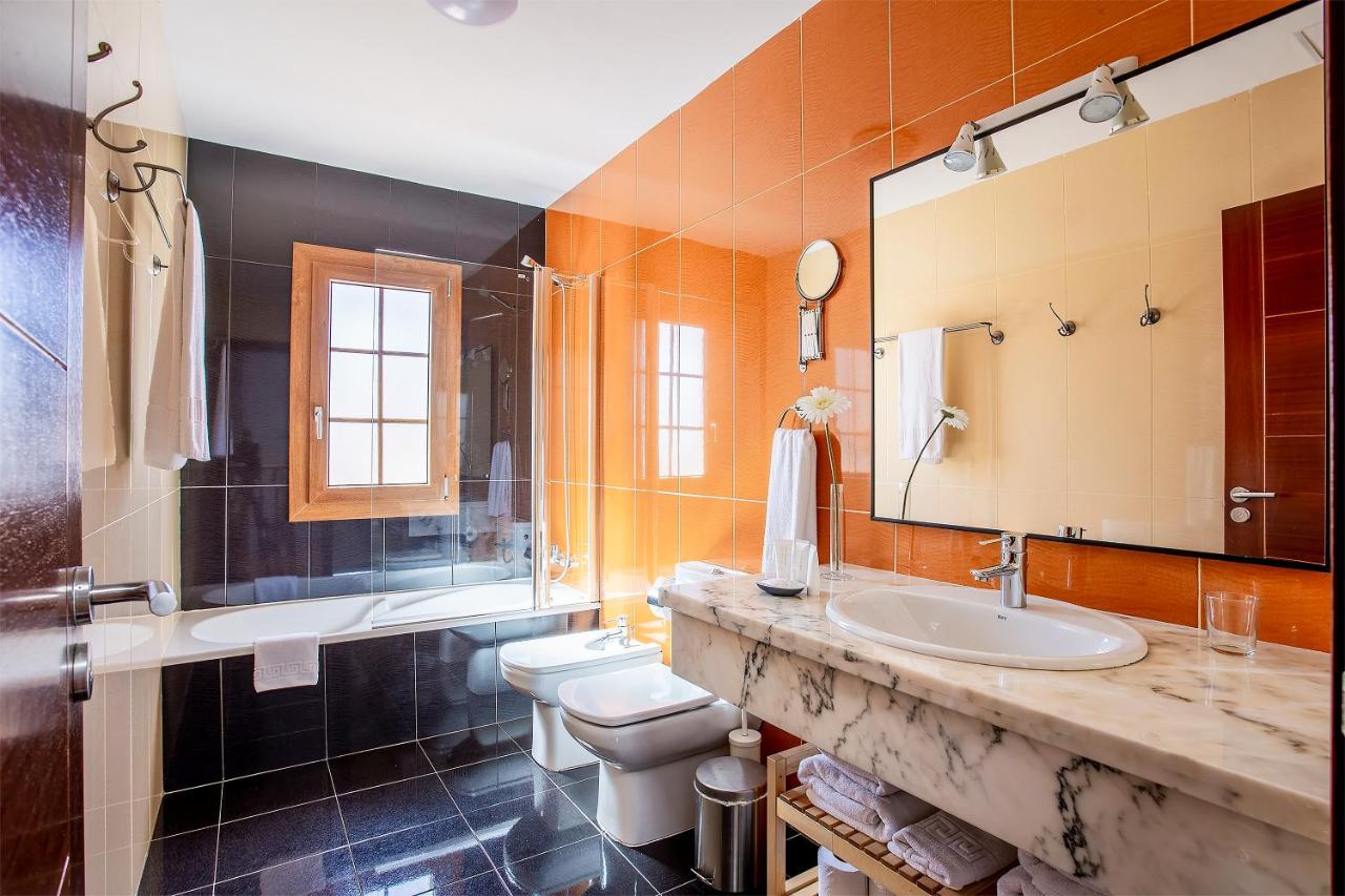 een badkamer met twee toiletten, een wastafel en een spiegel bij Las Caletas Village in Costa Teguise