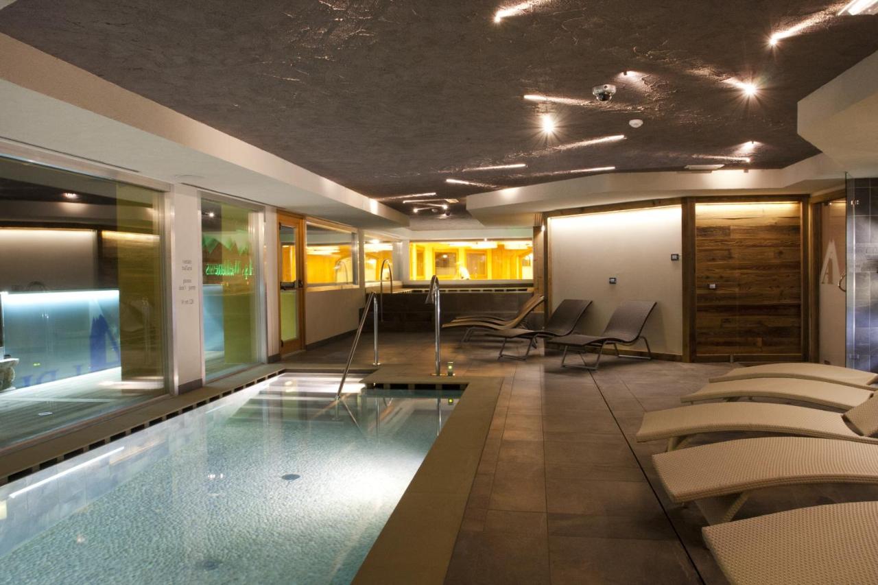 een hotelkamer met een zwembad en ligstoelen bij Hotel Delle Alpi in Passo del Tonale