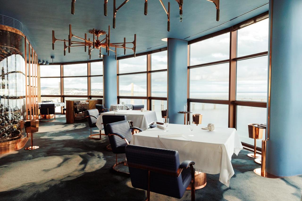 een eetkamer met tafels en stoelen en ramen bij MYRIAD by SANA Hotels in Lissabon