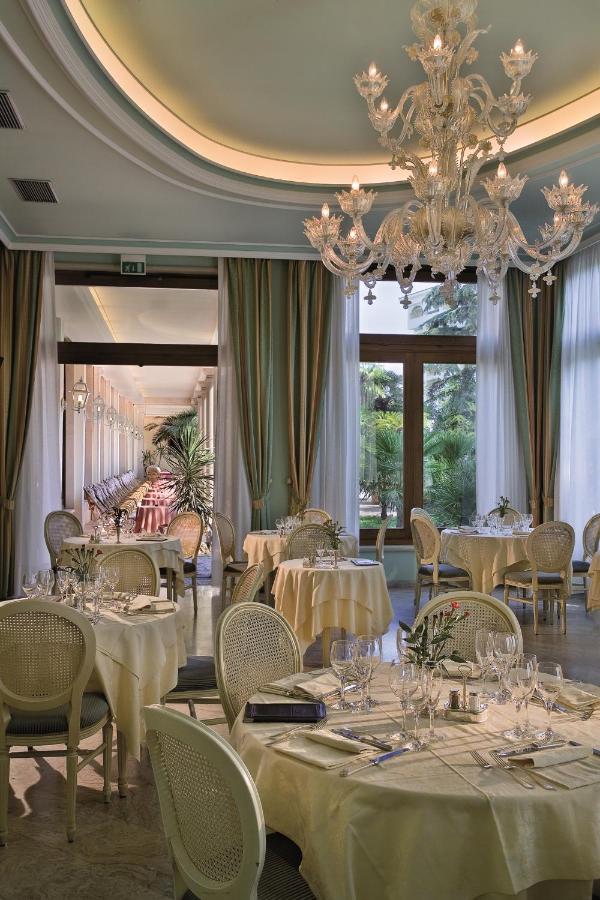 een restaurant met witte tafels en stoelen en een kroonluchter bij Palace Hotel Meggiorato in Abano Terme +37 foto's