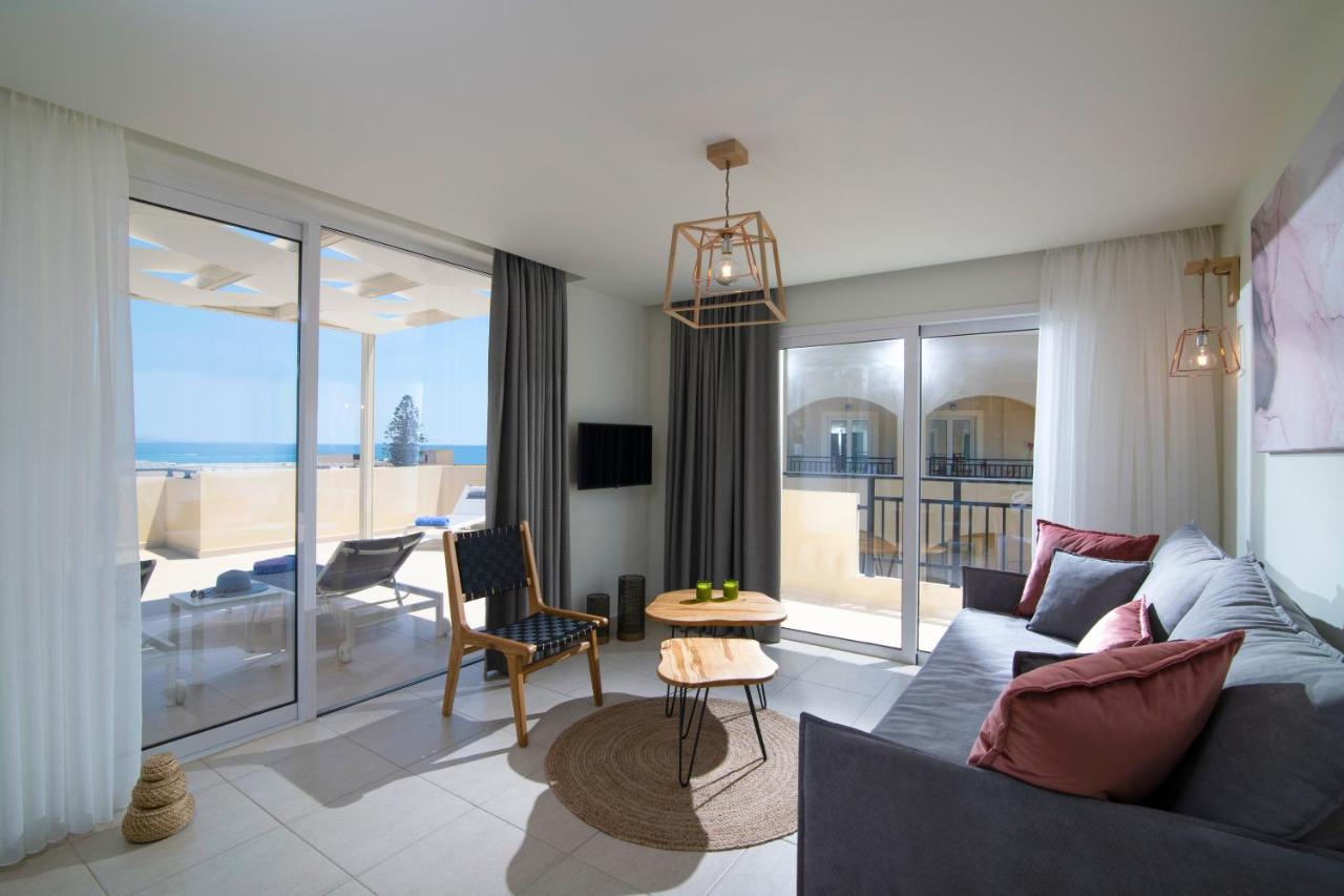 een woonkamer met een blauwe bank en uitzicht op de oceaan bij Rainbow Apartments in Stalida
