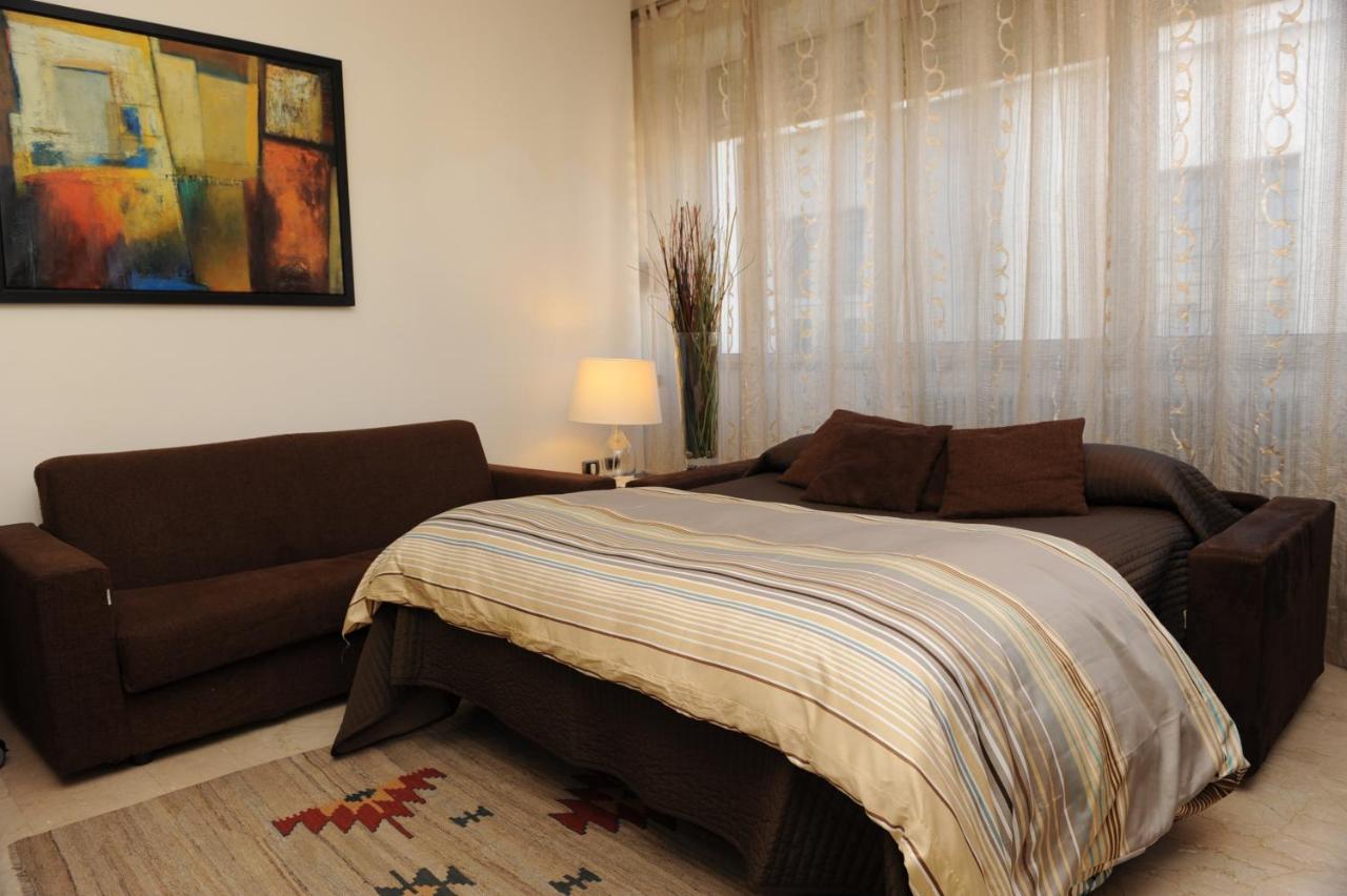 een slaapkamer met een bed en een bank bij Lux Appartamenti in Rome