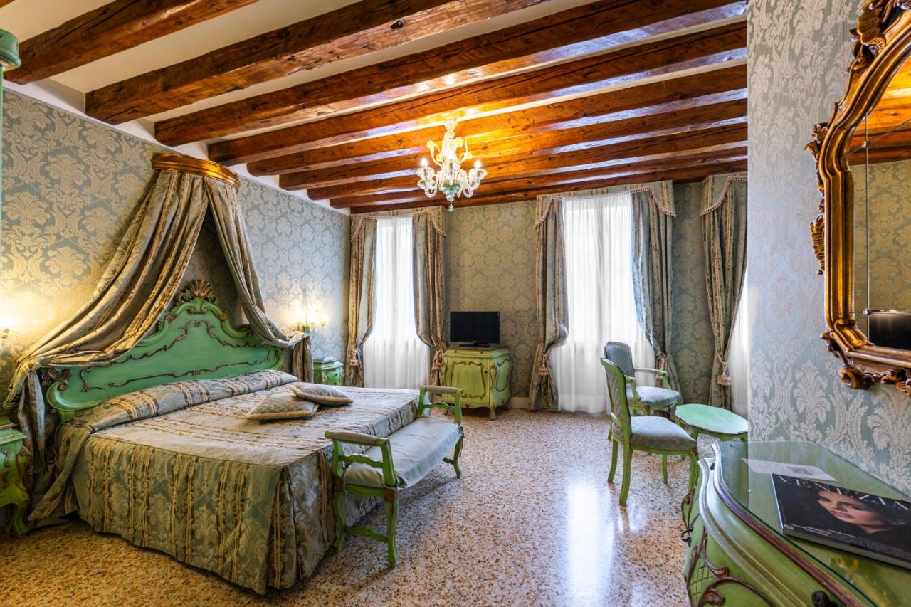 een slaapkamer met een groen bed en een tafel met stoelen bij Hotel Ca' Dogaressa in Venetië