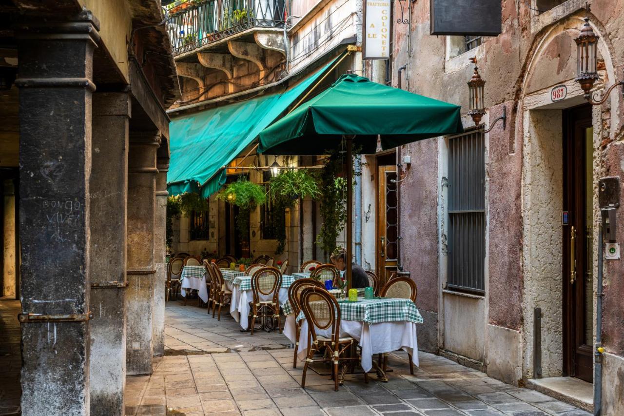een steegje met tafels en stoelen en een groene parasol bij Ca' Del Nobile in Venetië