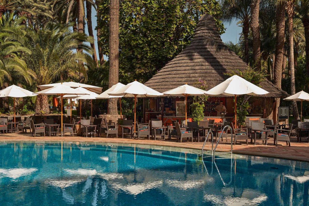 een zwembad met parasols en ligstoelen en een restaurant bij Seaside Palm Beach in Maspalomas