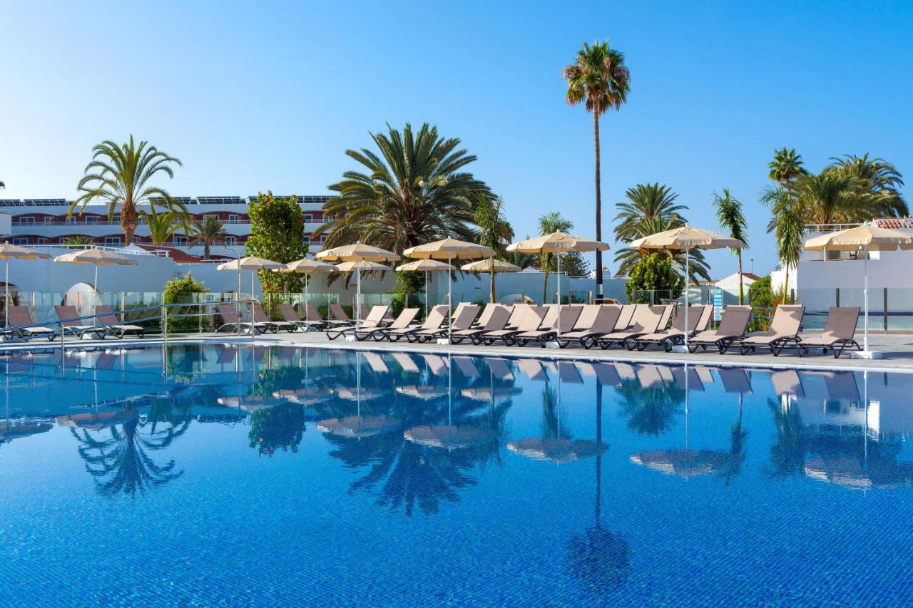 een zwembad met ligstoelen, parasols en palmbomen bij SOL by Meliá Barbacan in Playa del Inglés