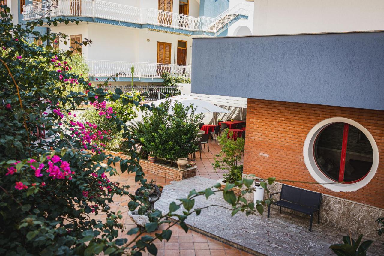 een buitenterras met roze bloemen en een gebouw bij Hotel Alexander in Giardini Naxos