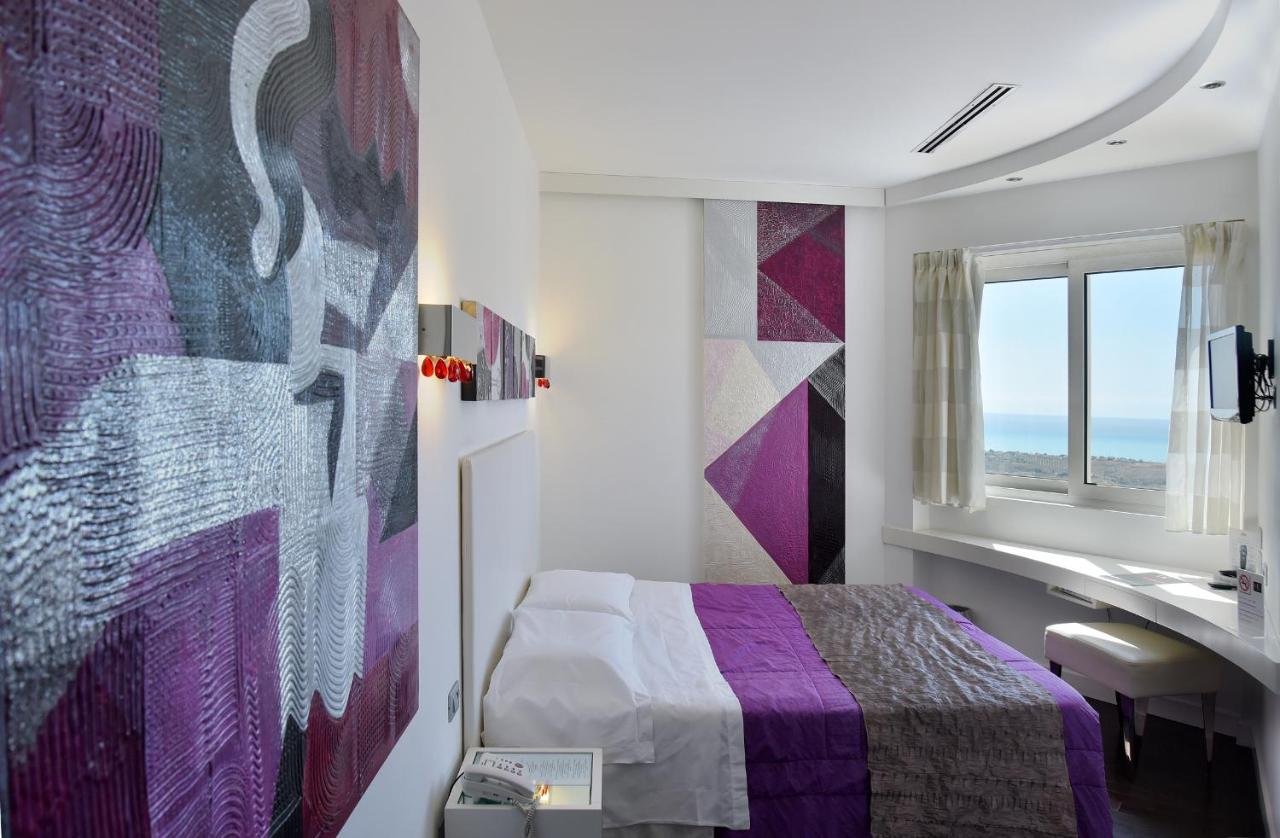 een slaapkamer met een bed, een wastafel en een raam bij Hotel Exclusive in Agrigento