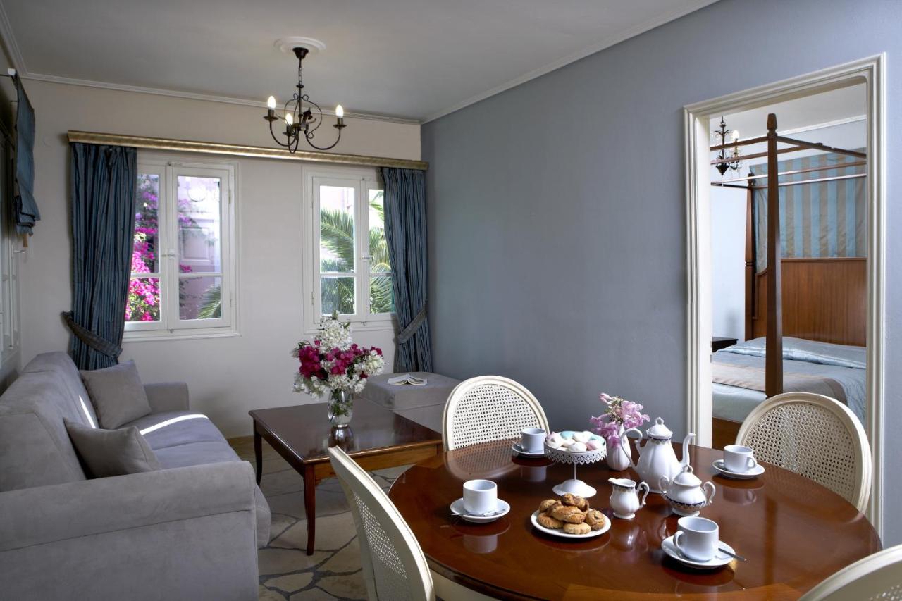 een woonkamer met een tafel, stoelen en een bank bij Dafnoudi Hotel Apartments in Fiskardho