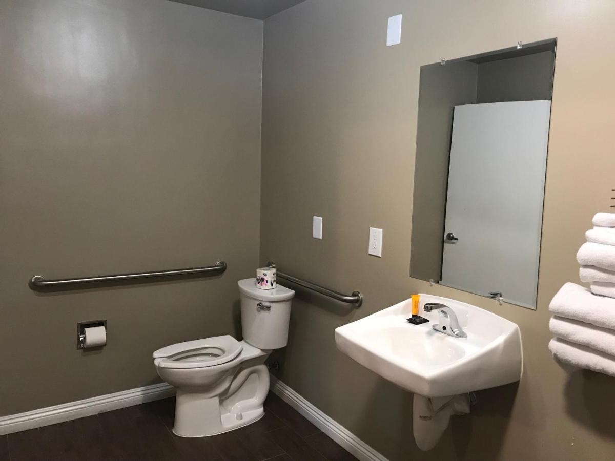 een badkamer met een toilet, een wastafel en een spiegel bij Corona inn in Corona
