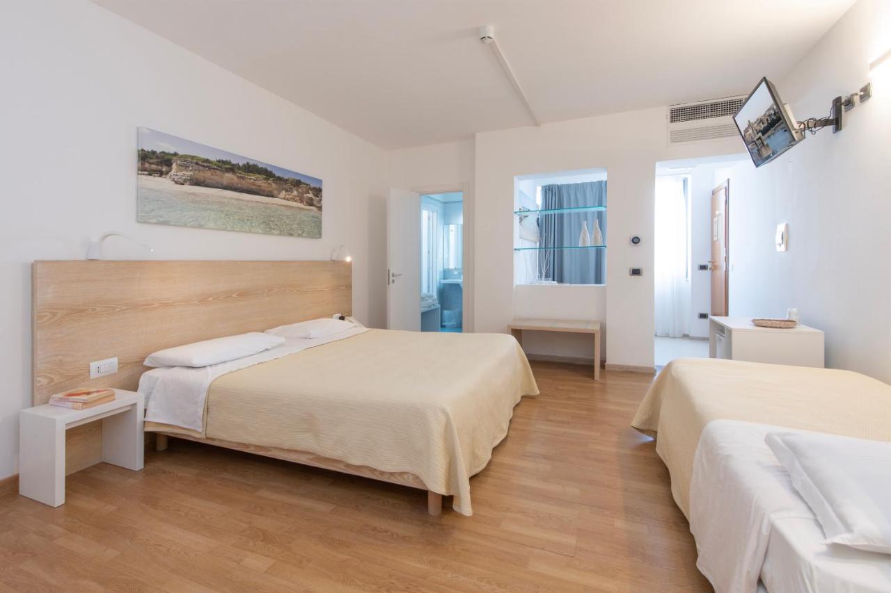 Twee bedden in een slaapkamer met witte muren en houten vloeren. bij Hotel Albània in Otranto