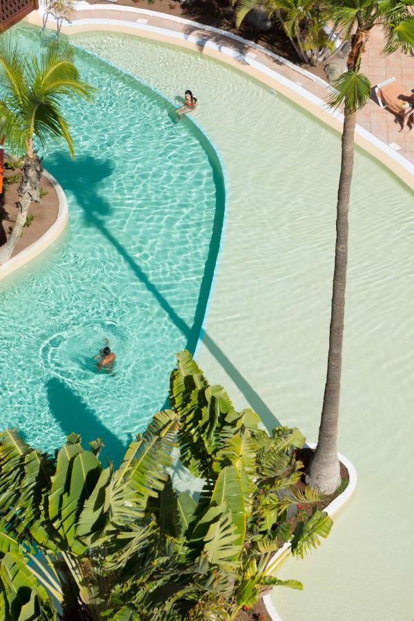 een bovenaanzicht van een zwembad met een palmboom bij Hotel Gran Canaria Princess - Adults Only in Playa del Inglés