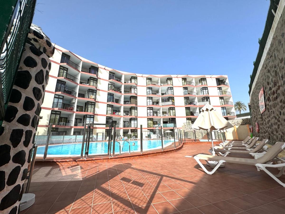 een groot appartementencomplex met een zwembad en ligstoelen bij Guinea Apartment in Playa del Inglés