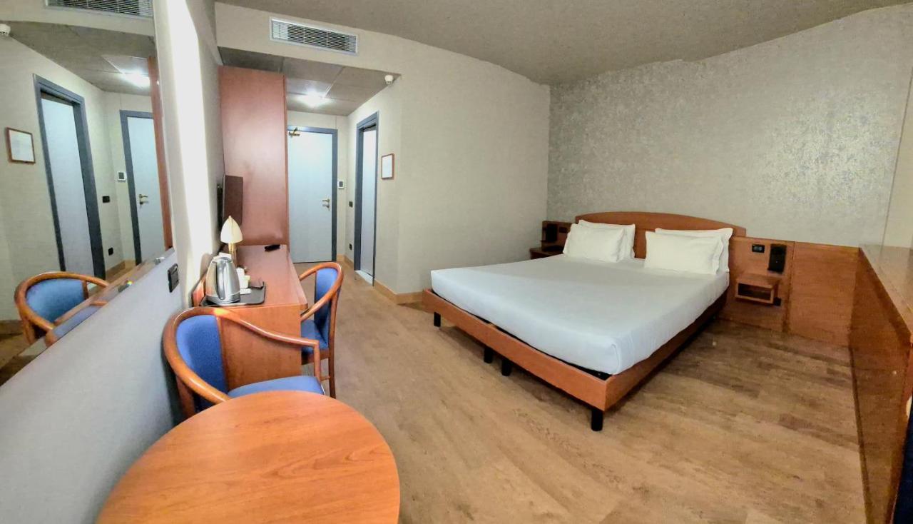 een slaapkamer met een bed, een tafel en stoelen bij Hotel Le Cerbaie in Altopascio