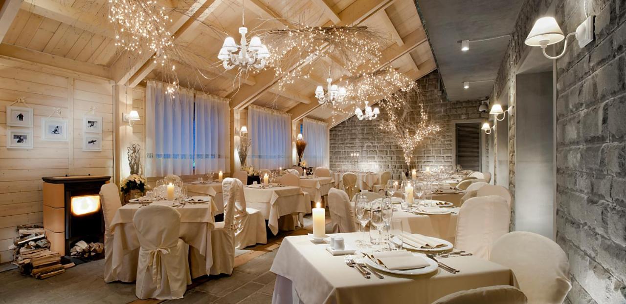 een restaurant met witte tafels en stoelen en kroonluchters bij Val di Luce SPA Resort in Abetone