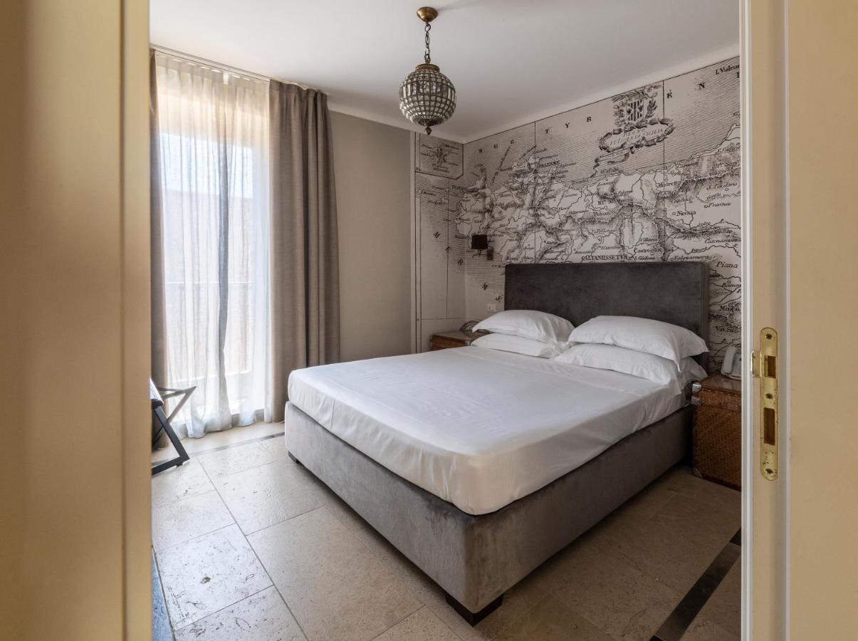 een slaapkamer met een bed en een muur met een kaart bij La Dépendance Hotel in Noto