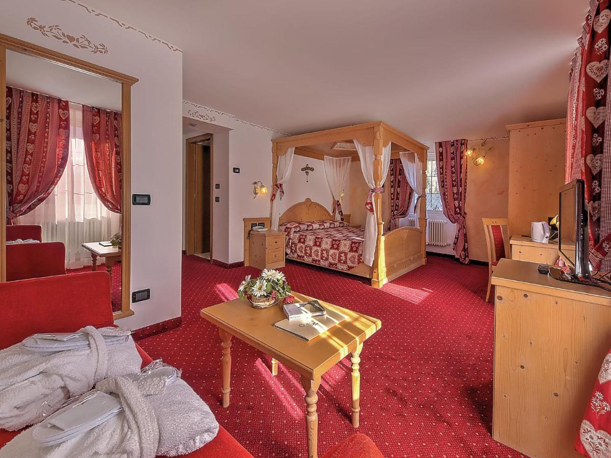 een hotelkamer met een slaapkamer met een hemelbed bij Al Posta Hotel 1899 in Baselga di Pinè