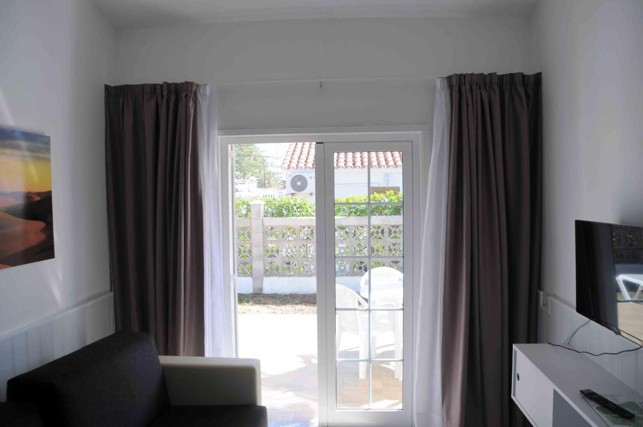 een woonkamer met een glazen schuifdeur naar een patio bij Bungalows Los Arcos in Playa del Inglés