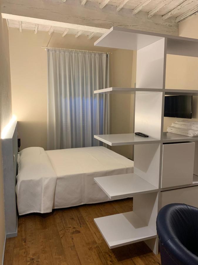 een slaapkamer met een wit bed en planken bij Albergo Roma in Buonconvento
