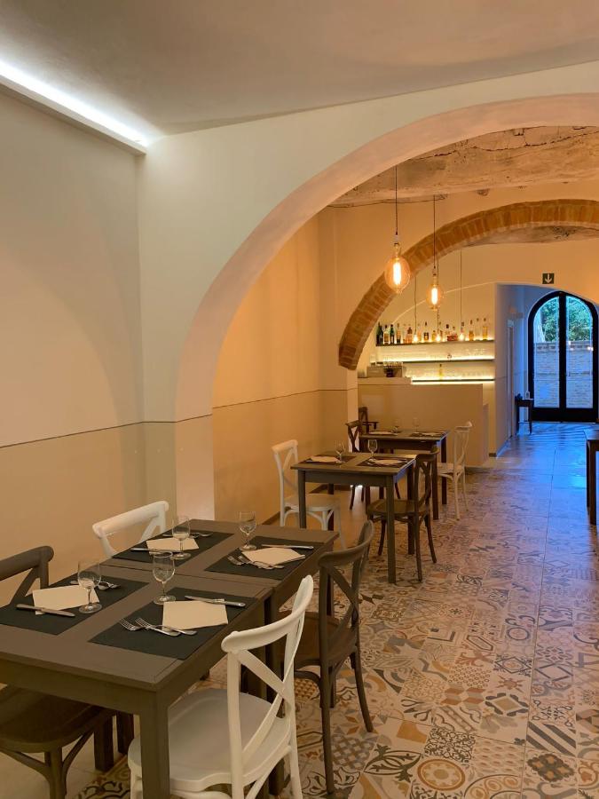 een eetkamer met tafels en stoelen en een boogdoorgang bij Albergo Roma in Buonconvento