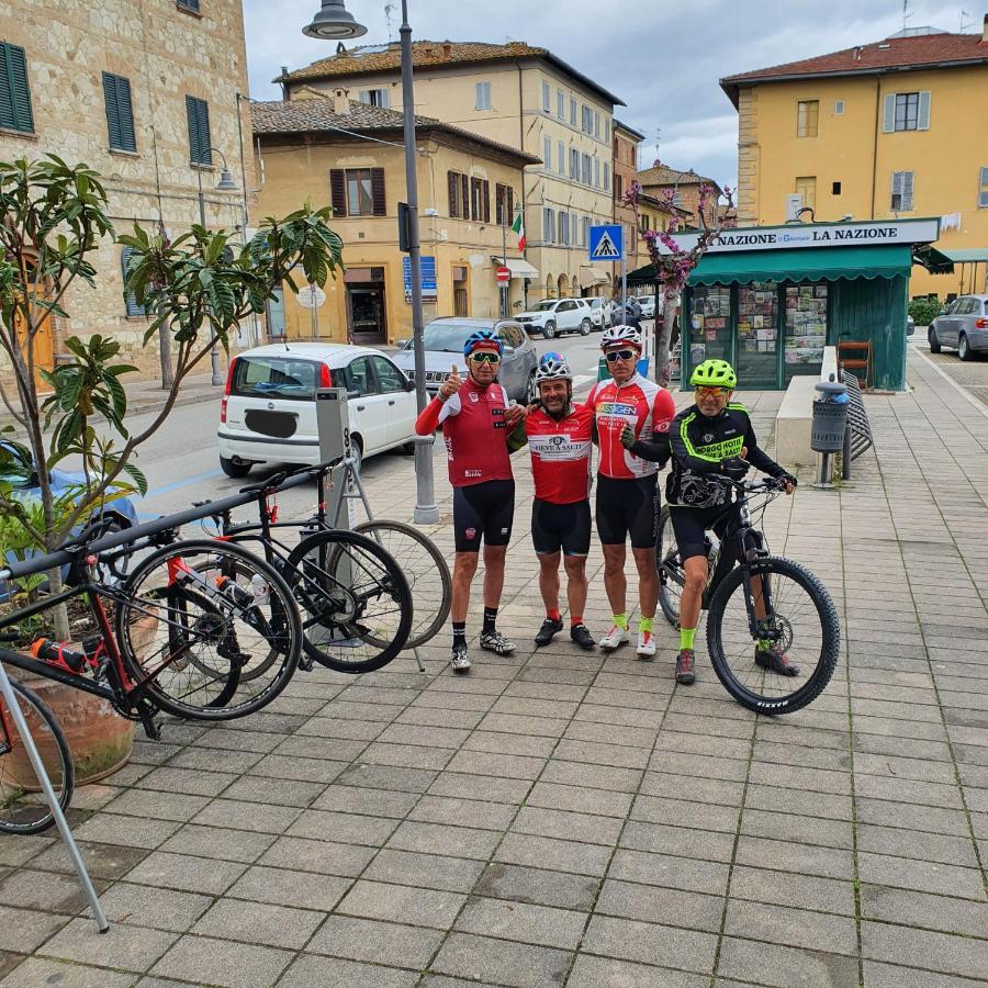 een groep mensen die naast fietsen op een stoep staan bij Albergo Roma in Buonconvento