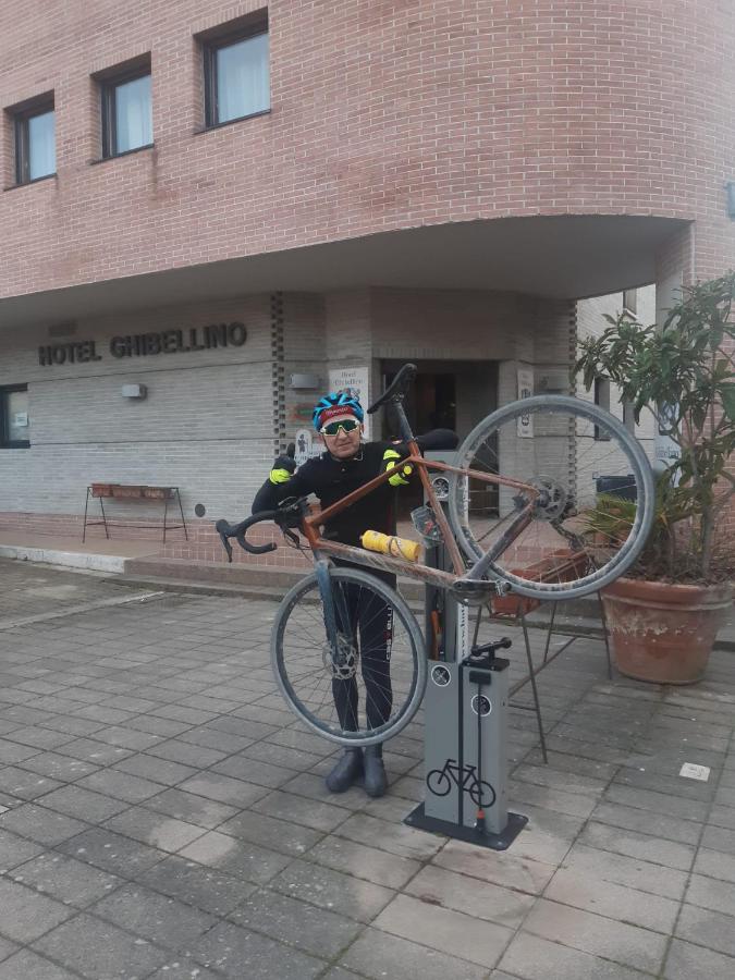 Een man houdt een fiets vast die op een standaard staat. bij Albergo Roma in Buonconvento +4 foto's