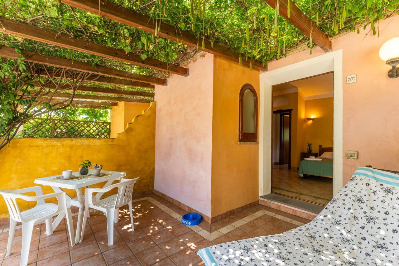 een terras met een tafel en stoelen en een gebouw bij Residence Baia delle Palme in Pula
