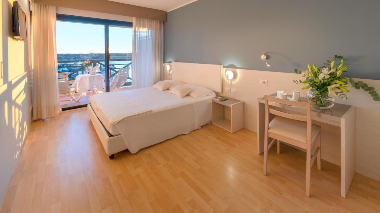 een slaapkamer met een bed, een bureau en een tafel bij Hotel Marina Uno in Lignano Sabbiadoro