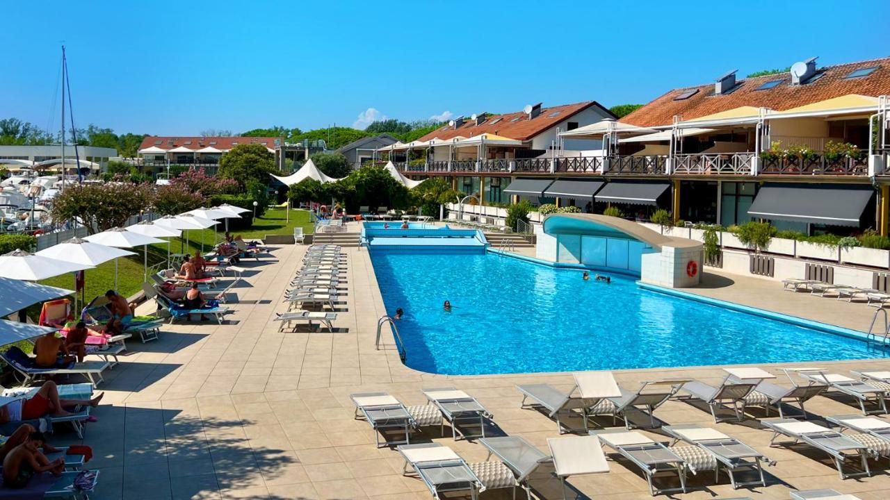 een groot zwembad met ligstoelen en parasols bij een hotel bij Hotel Marina Uno in Lignano Sabbiadoro