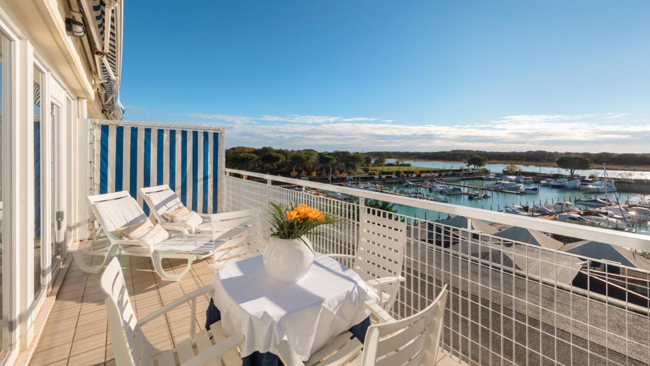 een balkon met een tafel en stoelen en een jachthaven bij Hotel Marina Uno in Lignano Sabbiadoro