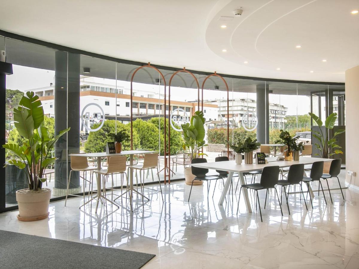 een eetkamer met een tafel, stoelen en planten bij B&B HOTEL Latina in Latina