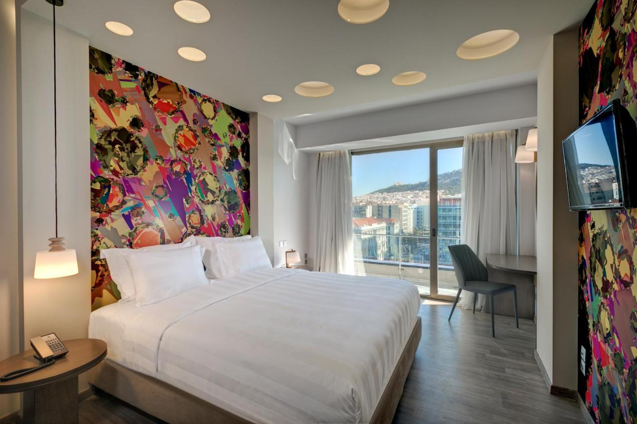een slaapkamer met een groot wit bed en een groot raam bij Athens Tiare by Mage Hotels in Athene