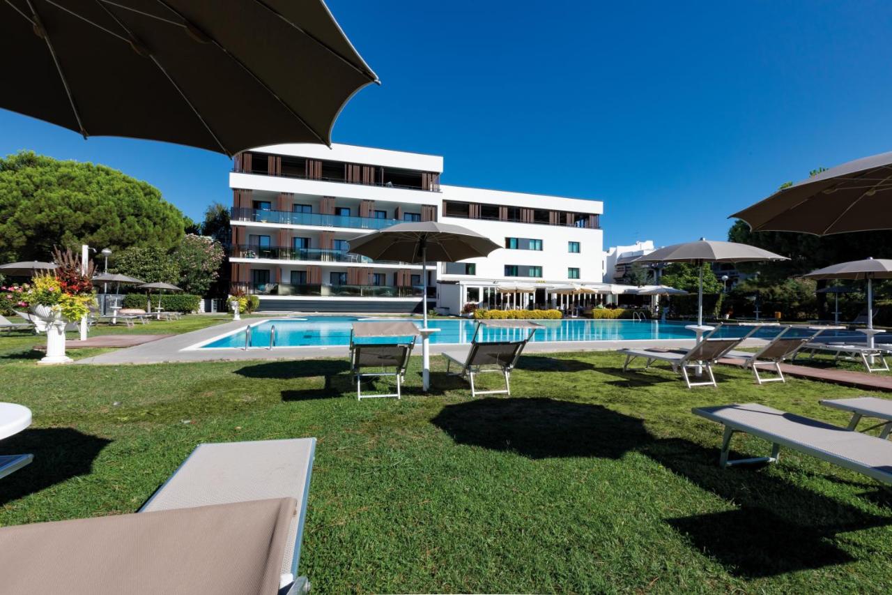 een hotel met een zwembad, ligstoelen en parasols bij Hotel Falcone in Lignano Sabbiadoro