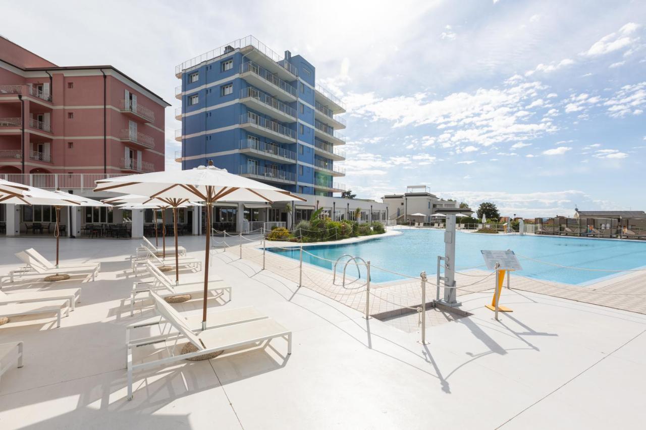 een zwembad met ligstoelen en parasols naast een gebouw bij Ai Pozzi Village & SPA in Loano