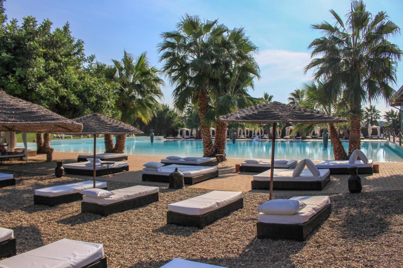 een zwembad met ligstoelen en parasols naast een resort bij Masseria & Spa LuciaGiovanni in Lecce