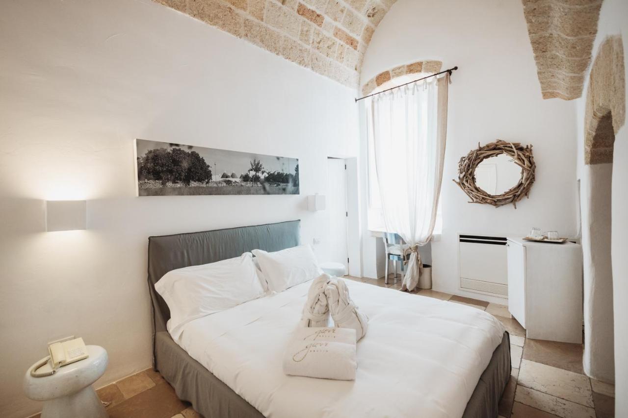 een slaapkamer met een bed met witte lakens en een spiegel bij Giovì Relais in Polignano a Mare +87 foto's