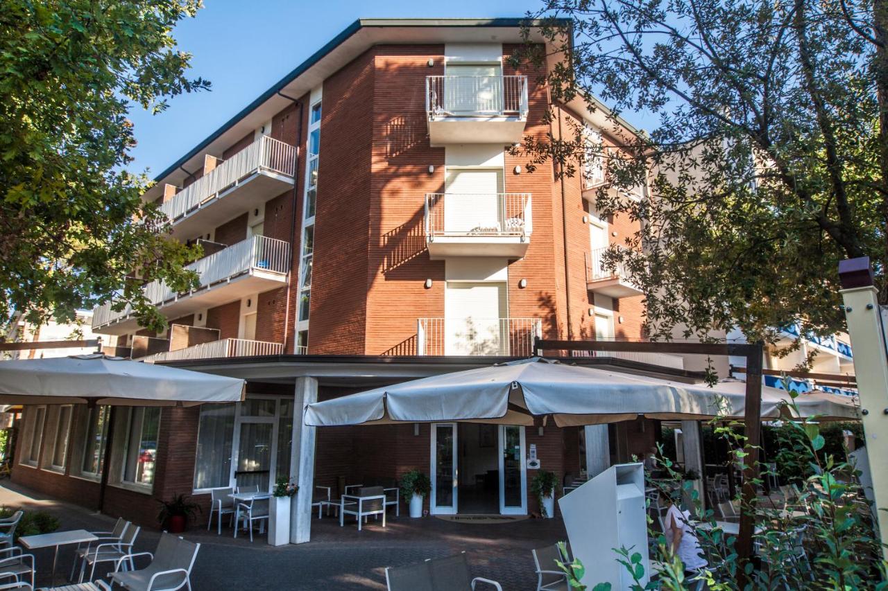 een gebouw met tafels en parasols ervoor bij Hotel Orsa Maggiore in Milano Marittima