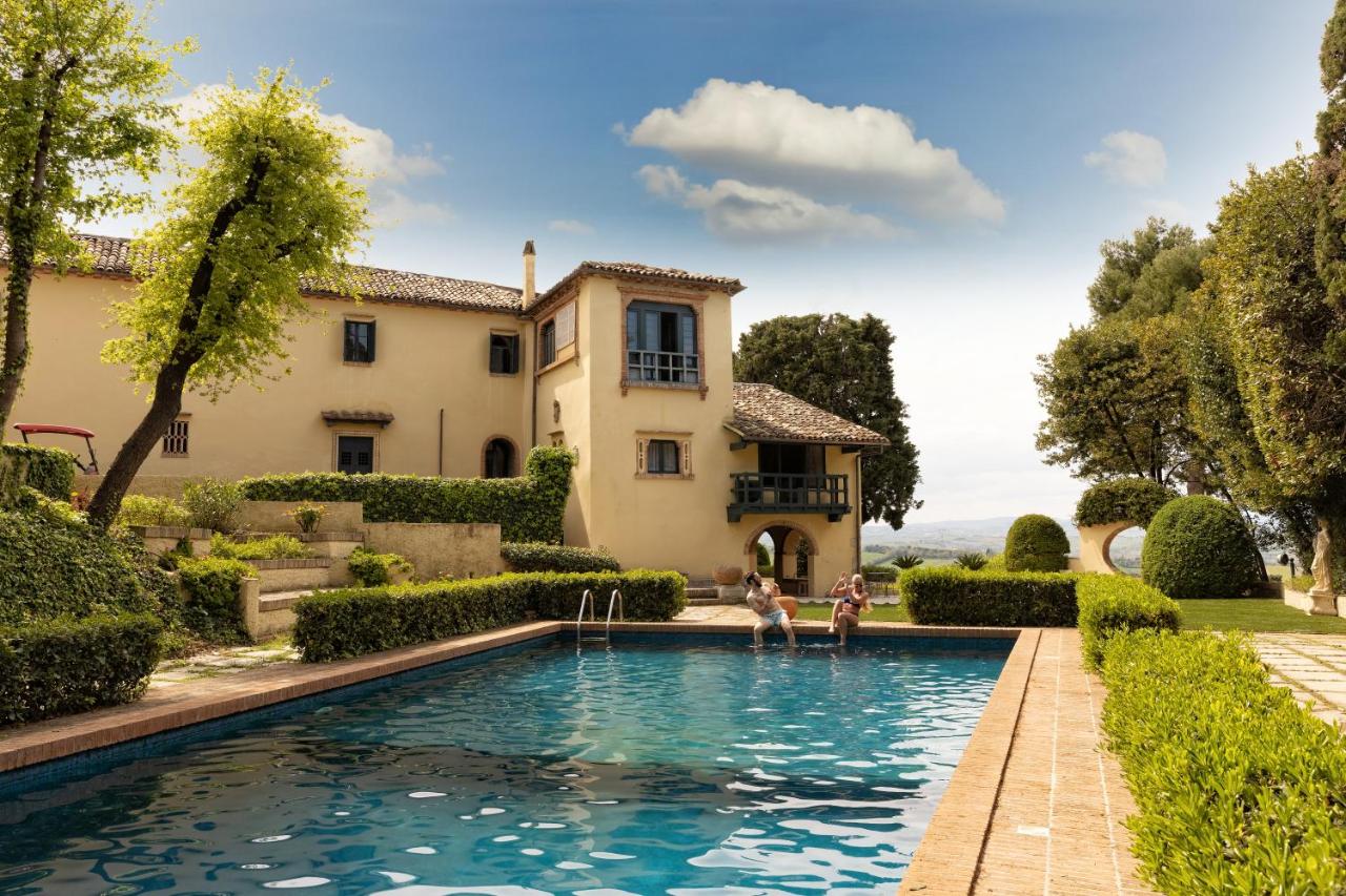 een huis met een zwembad waar twee mensen in zwemmen bij La Loggia Historic Resort - Albergo Diffuso in Gradara
