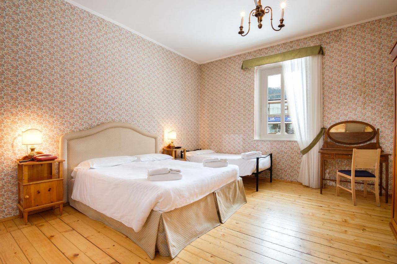 een slaapkamer met een groot bed en een spiegel bij TH San Martino - Majestic Dolomiti Hotel in San Martino di Castrozza