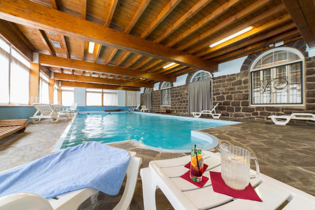 een zwembad met stoelen en een tafel in een gebouw bij TH San Martino - Majestic Dolomiti Hotel in San Martino di Castro