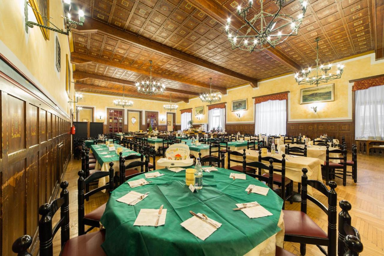 een grote eetkamer met groene tafels en stoelen bij TH San Martino - Majestic Dolomiti Hotel in San Martino di Castrozza