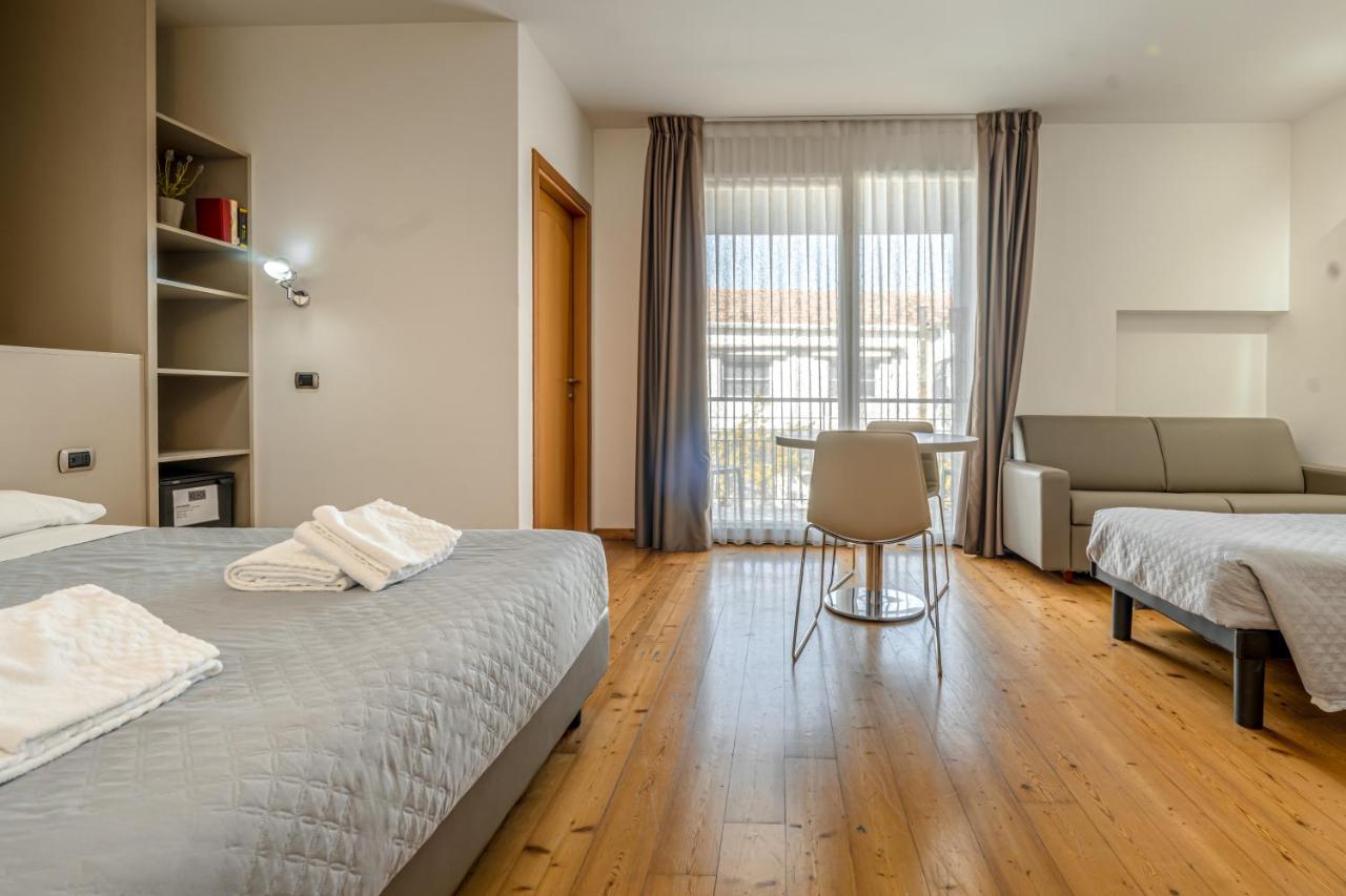 een slaapkamer met twee bedden, een tafel en een bank bij Hotel Rubicone in Savignano sul Rubicone