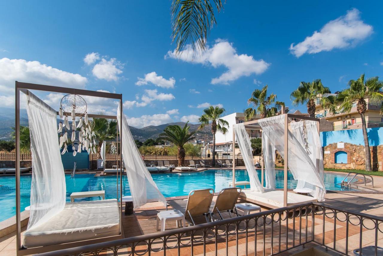 een zwembad bij een resort met ligstoelen en een trouwboog bij Oasis Studios in Malia